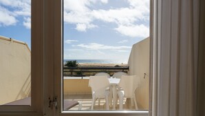 A balcony with a view of the beach and ocean.