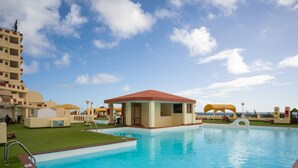 A swimming pool with a lifeguard station, a lounge area, and a view of the ocean.