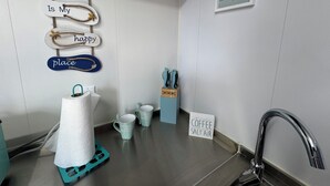A kitchen with a coffee sign, a towel rack, and a sign that reads "The Beach is my happy place". - Rincon Sunset Studio (Rincon)