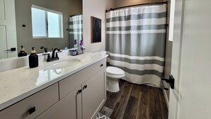 A bathroom with a white sink, black faucets, a toilet, and a striped shower curtain.