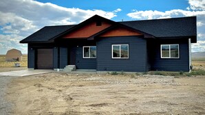 A modern two-story house with a dark exterior, a red roof, and a garage.