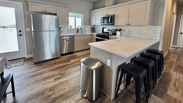 A modern kitchen with stainless steel appliances, a large island, and bar stools.