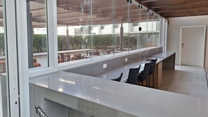 Et moderne barområde med glasafskærmning, siddepladser og udsigt til terrassen.