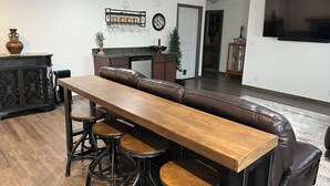 A modern kitchen with a dining area featuring a long wooden table and leather seating. - Spacious 4-bedroom house with AC, WiFi in NW Lincoln (Lincoln)
