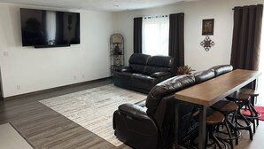 A modern living room with a leather sofa, a wooden coffee table, and a TV mounted on the wall. - Spacious 4-bedroom house with AC, WiFi in NW Lincoln (Lincoln)