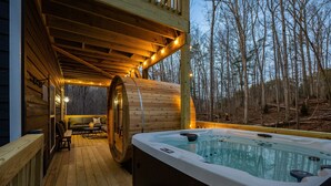 A wooden deck with a hot tub, wooden barrel, and a sofa with cushions.