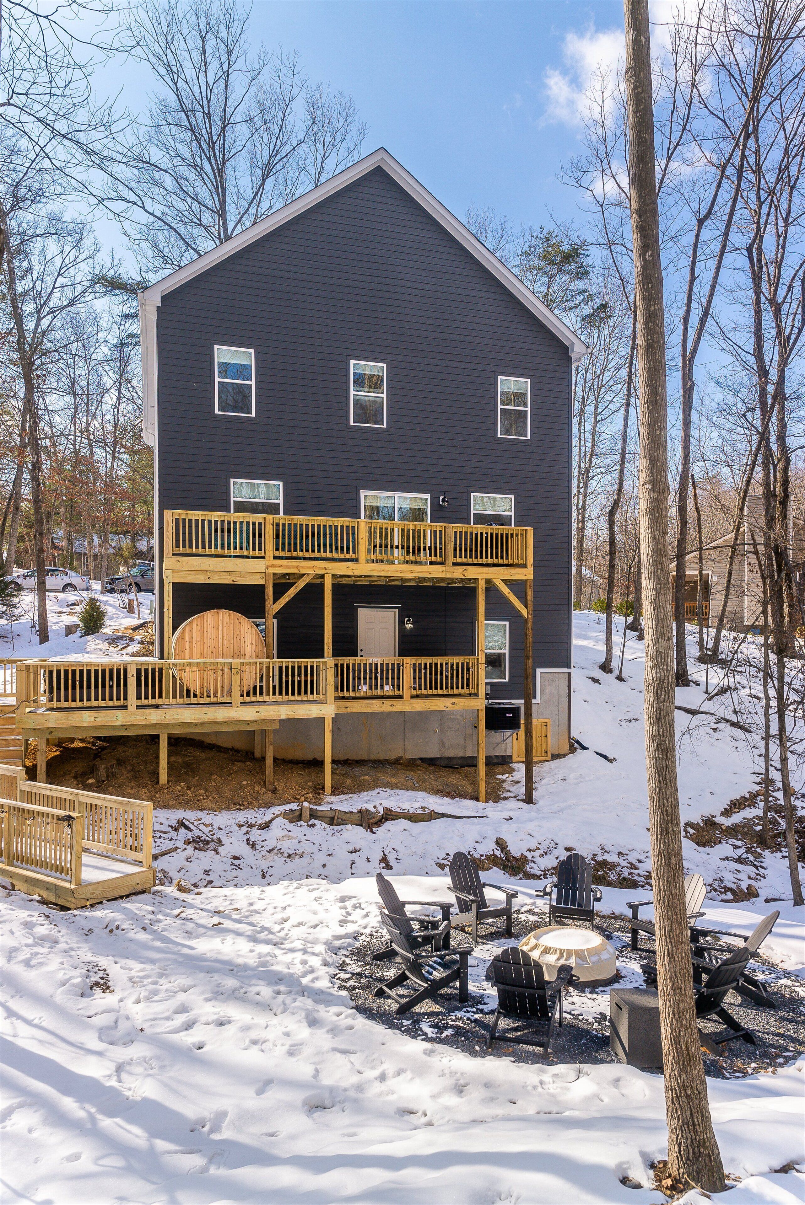 A two-story house with a deck, outdoor seating, and a fire pit.