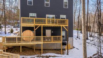 A two-story house with a deck, outdoor seating, and a fire pit.
