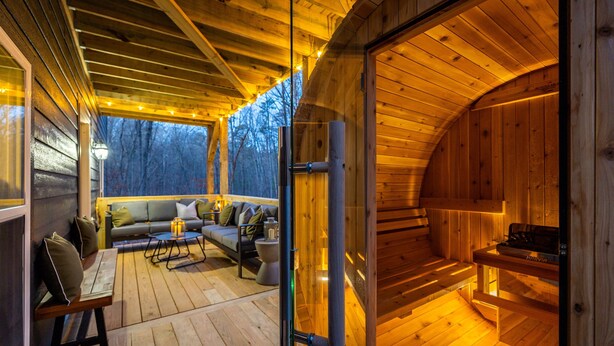 A wooden cabin interior with a sofa, table, and a fireplace.