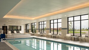 A large indoor swimming pool with clear blue water, surrounded by lounge chairs and tables, large windows offering views of the outside. - Hyatt Place Billings (Billings)