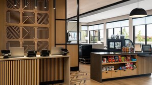 A modern reception area with a wooden reception desk, a coffee machine, and a snack display. - Hyatt Place Billings (Billings)