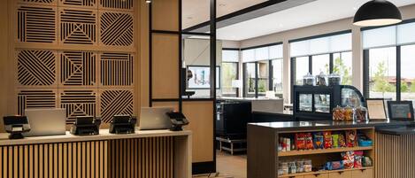 A modern reception area with a wooden reception desk, a coffee machine, and a snack display.