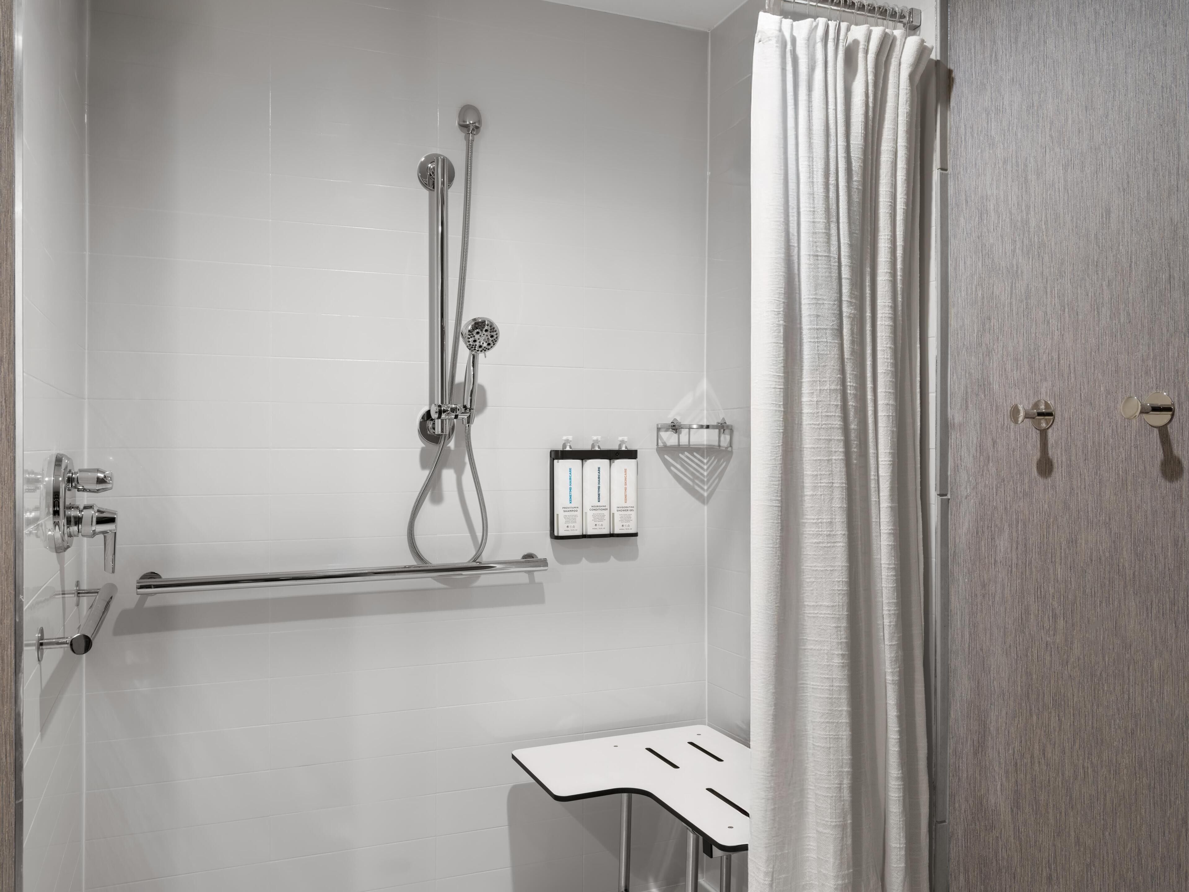 Ein Badezimmer mit Dusche, Handtuchhalter und Wandseifenspender.