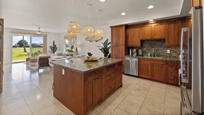 A spacious kitchen with wooden cabinets, a large island, and a view to the outdoors.