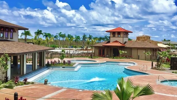 A resort with a large pool, palm trees, and a building with a red roof.