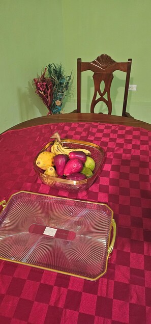 Una alfombra roja a cuadros, una bandeja de cristal con frutas y una silla de madera.