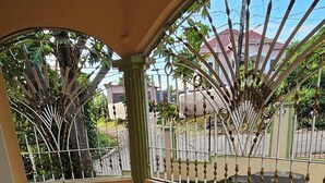Ein überdachter Balkon mit Fliesenboden und schmiedeeisernem Geländer.