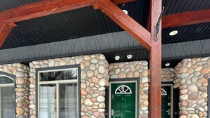 A building with a stone facade, large windows, and a green door. - 2 Bedroom at Mystic Springs Chalets & Hot Pools (Canmore)