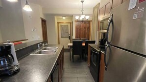 A kitchen with a stainless steel refrigerator, a coffee maker, and a sink.