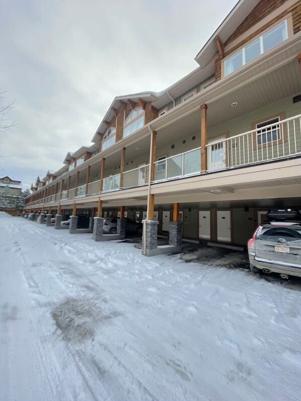A multi-story hotel with balconies, parking garage, and snow-covered ground.