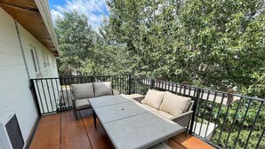 Een terras buiten met een bank, een tafel en een leuning.