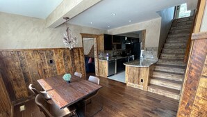 Een ruime eethoek met een houten tafel en stoelen, een keuken op de achtergrond en een houten trap.