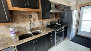 Een moderne keuken met donkere kastjes, een granieten aanrechtblad, een roestvrijstalen koelkast en een inbouwoven.