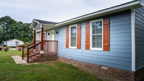 A single-story house with a front porch, a brick foundation, and a blue exterior. - Charming 2-bedroom farmhouse in nice Wendell with AC, WiFi (Wendell)