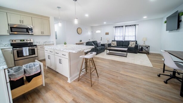 A modern kitchen with white cabinets, stainless steel appliances, and a marble countertop. - Charming 2-bedroom farmhouse in nice Wendell with AC, WiFi (Wendell)