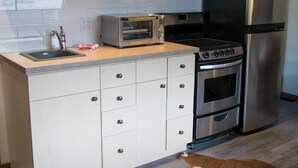 A modern kitchen with white cabinets, a microwave, an oven, and a refrigerator. - Yam 27/28 - Upper 2 Bedroom K/Q (Dead Man's Flats)