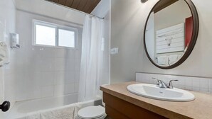 A bathroom with a bathtub, toilet, sink, and a mirror.