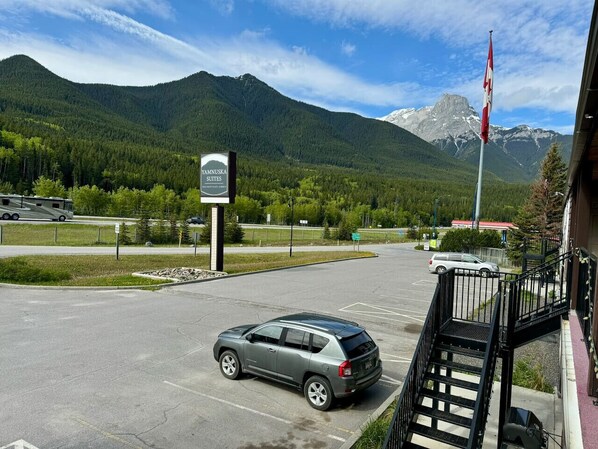 Un estacionamiento con un cartel de Yamnuska Suites, montañas al fondo y una bandera.