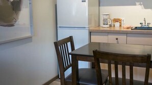 A kitchen with a refrigerator, microwave, and coffee maker. There is a wooden table and chairs. - Yam 23 - Upper Studio with King (Dead Man's Flats)