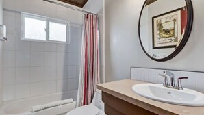 Ein Badezimmer mit Dusche, Toilette, Waschbecken und einem Fenster.