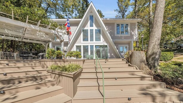 A modern house with a triangular roof, a flag, and a staircase leading to the entrance.