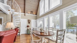 A dining area with a wooden table, white chairs, and a red sofa.