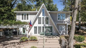 A modern house with a triangular roof, a porch with outdoor furniture, and a flag.