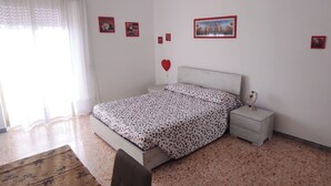 Een slaapkamer met een bed, nachtkastje en foto's aan de muur.