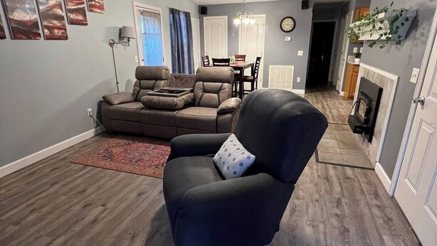 Ein Wohnzimmer mit einem dunkelbraunen Ledersessel, einem Deckenventilator und einem Essbereich mit einer Kristallleuchtre.