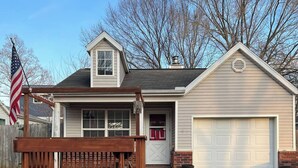 Ein eingeschossiges Haus mit Garage, einer Veranda mit Bank und einer amerikanischen Flagge.