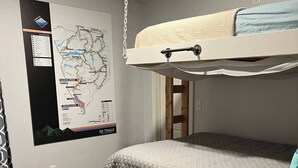 Ein Zimmer mit einem Etagenbett, einer an der Wand hängenden Karte und einem Holzboden.