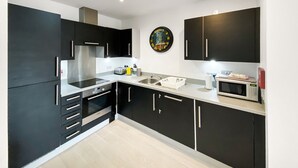 A modern kitchen with black cabinets, stainless steel appliances, and a white countertop. - Argyle Street - Apartment 2 (Glasgow)