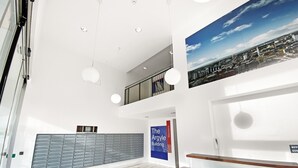 A spacious lobby with a reception desk, a large wall-mounted sign for The Argyle Building, and a cityscape view. - Argyle Street - Apartment 2 (Glasgow)