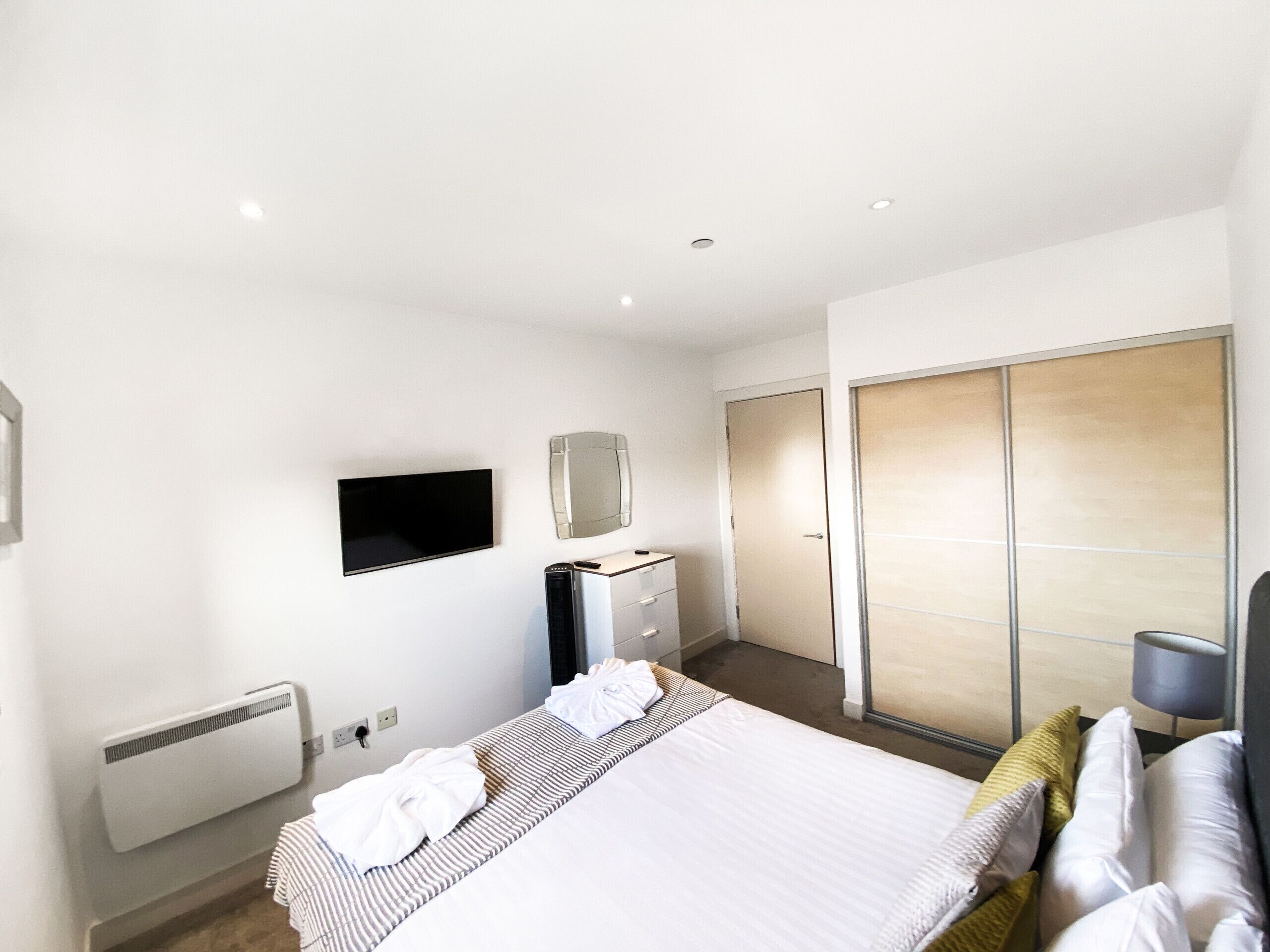 Une chambre d’hôtel moderne équipée d’un lit, d’un téléviseur à écran plat, d’une commode et d’une armoire.