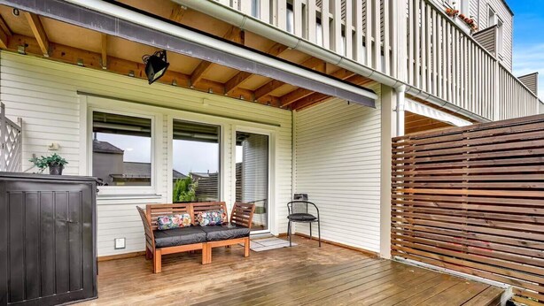 A wooden deck with a bench and a chair, a covered porch, and a wooden fence. - Apartment near Oslo, Drammen, and a lake (Buskerud)