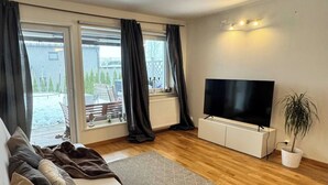 A modern bedroom with a large bed, a flat-screen TV, and a view of the outdoors through large windows. - Apartment near Oslo, Drammen, and a lake (Buskerud)