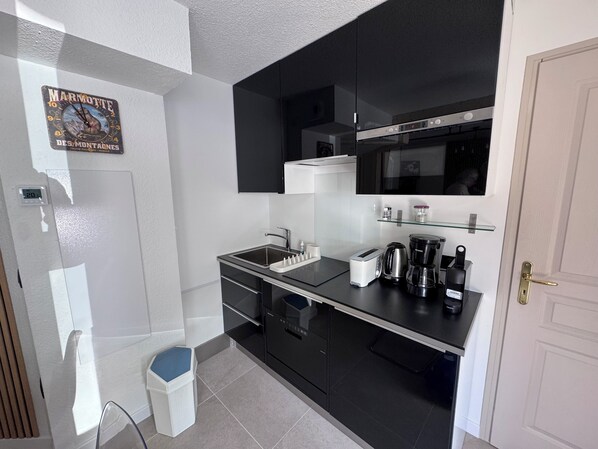 A modern kitchen with a black countertop, stainless steel appliances, and a white trash bin. - Apartment 4 Adults and one child - Flumet - heated swimming pool (Flumet)
