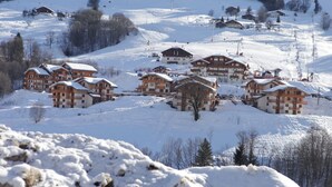A snow-covered ski resort with multiple chalet-style buildings, ski lifts, and a clear view of the surrounding snowy landscape. - Apartment 4 Adults and one child - Flumet - heated swimming pool (Flumet)