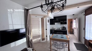 A modern kitchen with black cabinets, a dining table with chairs, and a chandelier. - Apartment 4 Adults and one child - Flumet - heated swimming pool (Flumet)