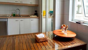 Una cucina moderna con mobili bianchi, un lavello in acciaio inossidabile e un tavolo di legno con un cesto.